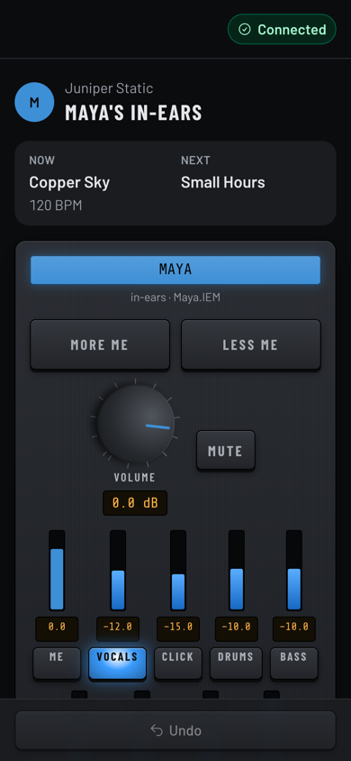 A phone showing Maya's in-ears with the current and next song, More me and Less me, a volume knob and sliders for vocals, click, drums and bass.